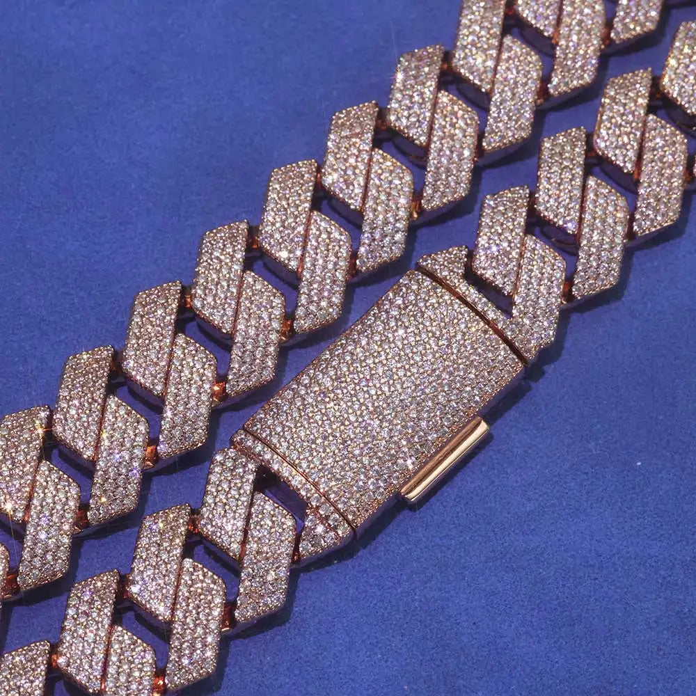 A close-up of a wide Cuban link chain bracelet paved with small clear stones in a rose gold-tone setting, shown on a textured blue background.